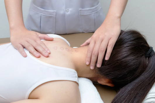 Girl is lying on the massage table while chiropractor checking her neck and spine