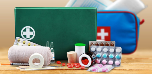 Blue and green first aid kit with pills and different supplies on wooden background